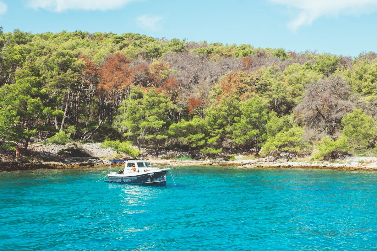 Boat anchored in Adriatic Sea with forests in Croatia