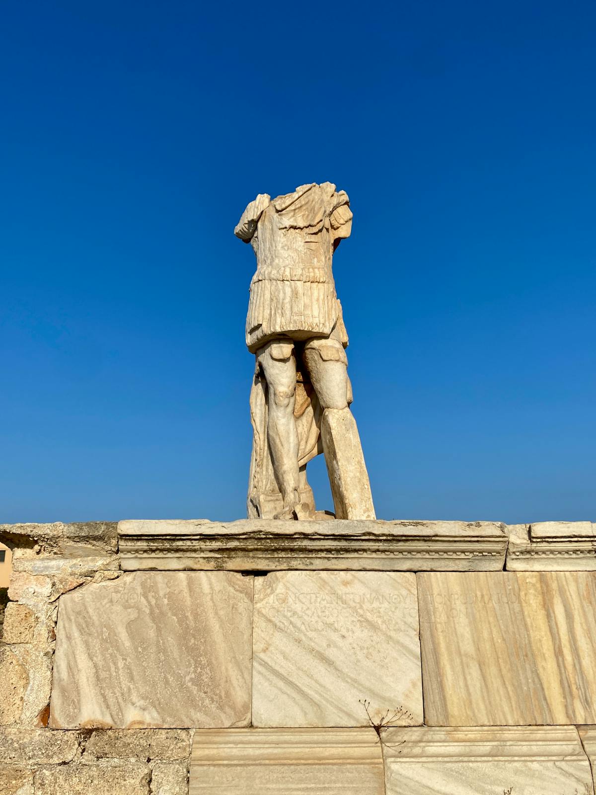 Ancient marble statue on Delos island against a clear blue Greek sky