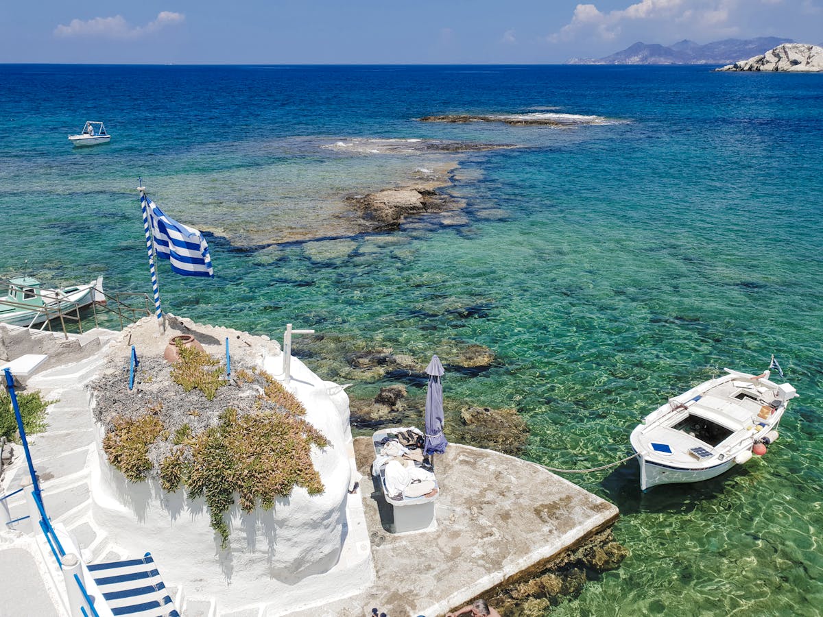 Greek island harbor with boats moored in crystal-clear turquoise water