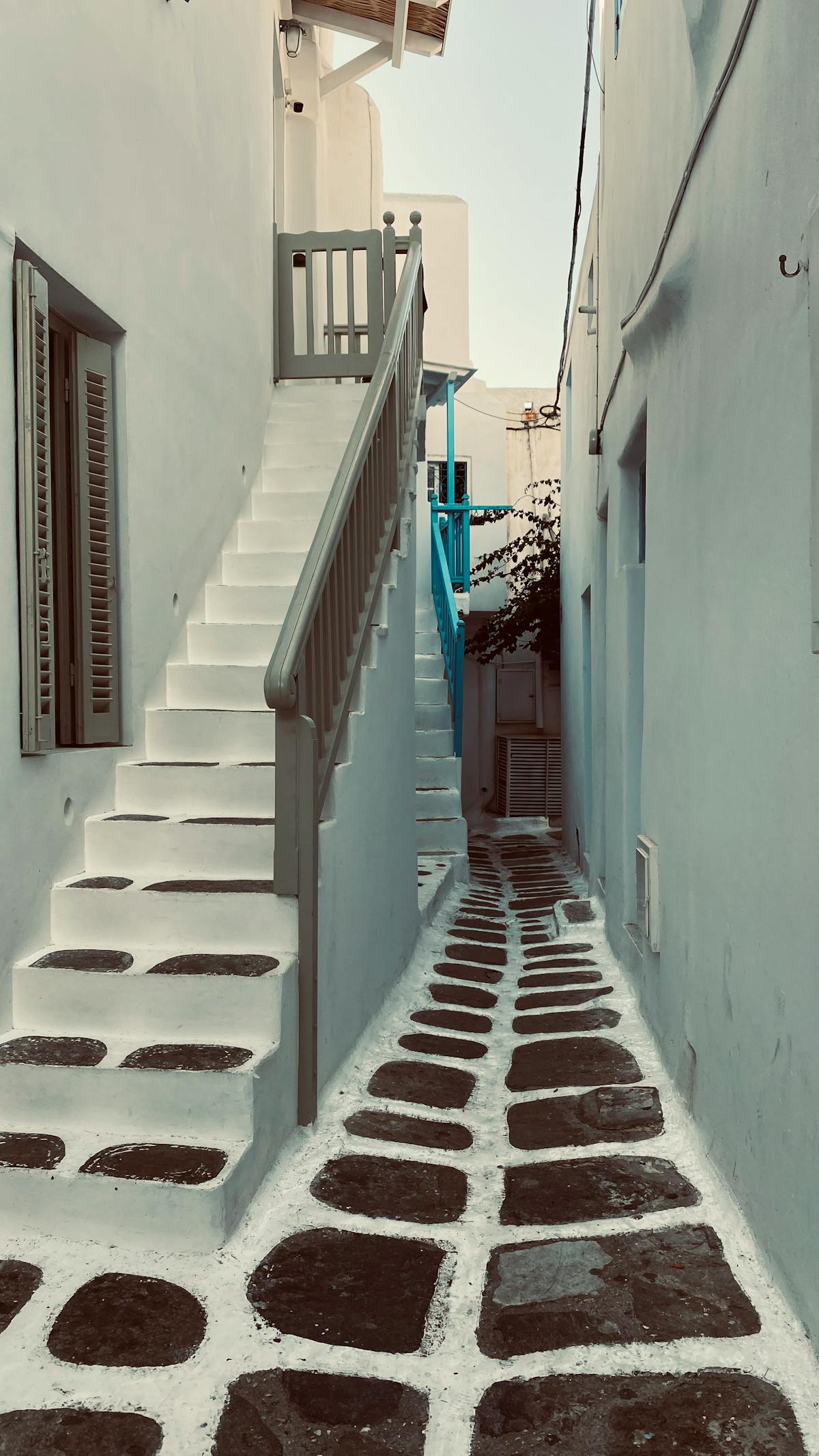 Narrow whitewashed alleyway in Mykonos town with blue accents