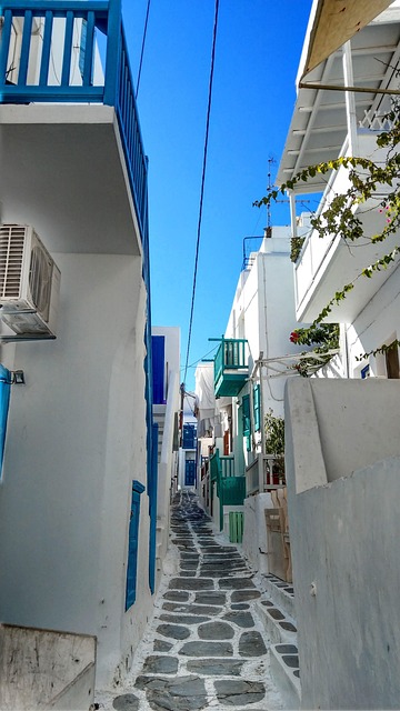 White cobblestone alley in Mykonos with bougainvillea and blue doors