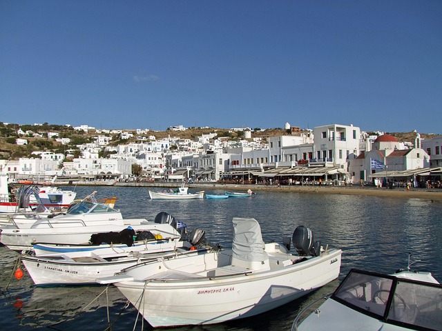 Boats moored at Mykonos harbor with white buildings in background