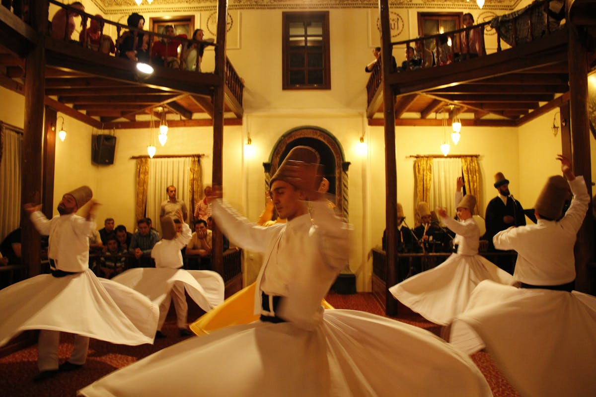 Audience watching whirling dervishes perform in white robes