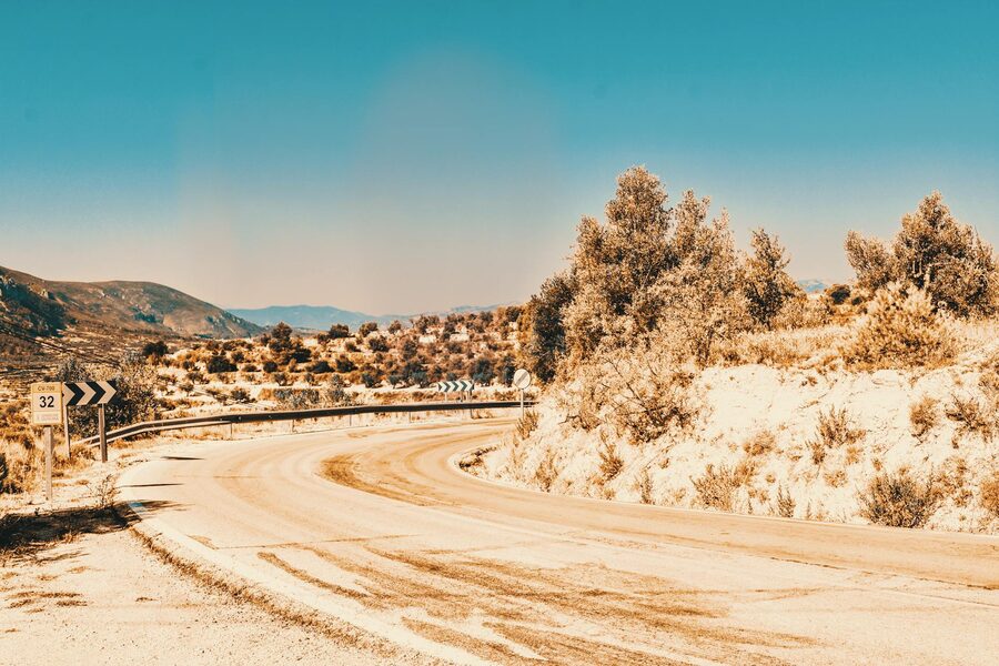 Desert road cutting through arid Spanish landscape under clear sky