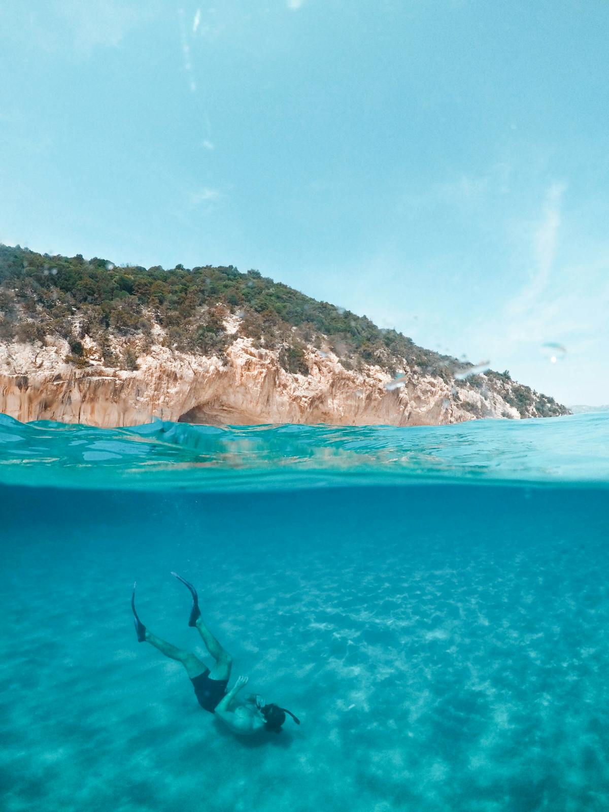 A diver exploring turquoise underwater waters off the coast of Sardinia