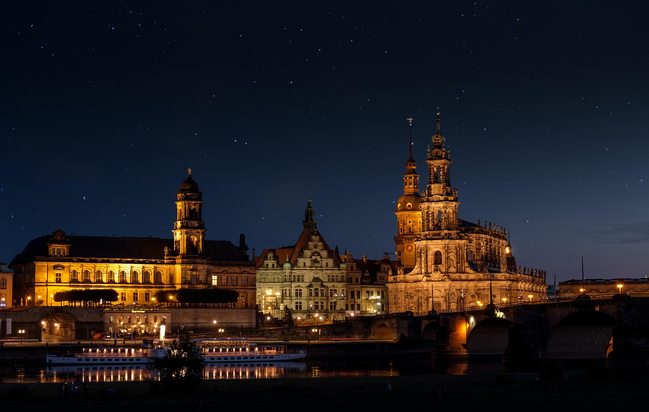 Dresden Hofkirche and palace illuminated at night beside the Elbe River with starry sky