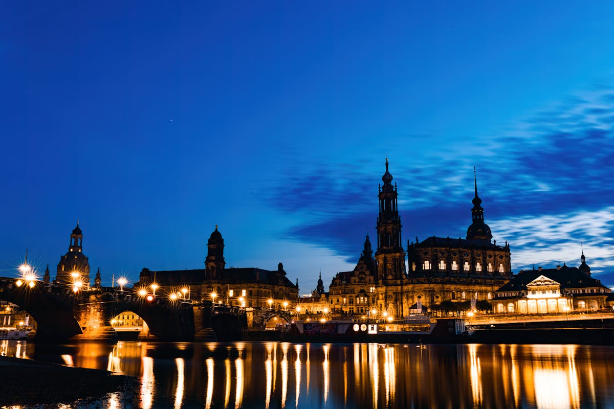 Dresden cathedral and historic buildings lit up at night with reflections in the Elbe River