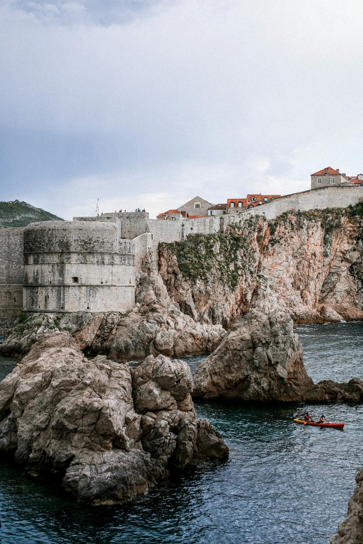 Dubrovnik's ancient fortress and rocky coastline with kayakers