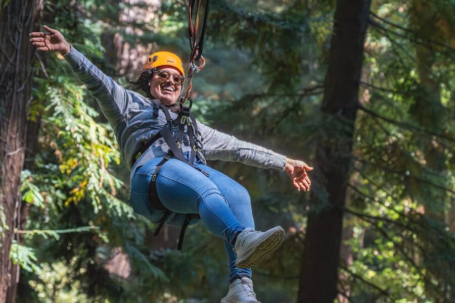 Woman ziplining through lush forest canopy