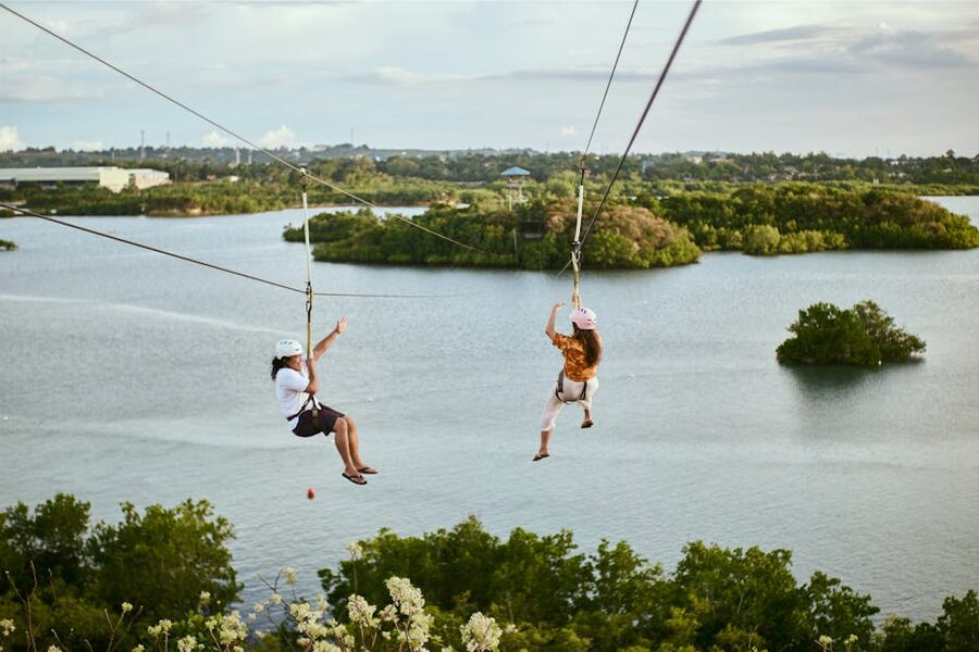 Two people zipline over water