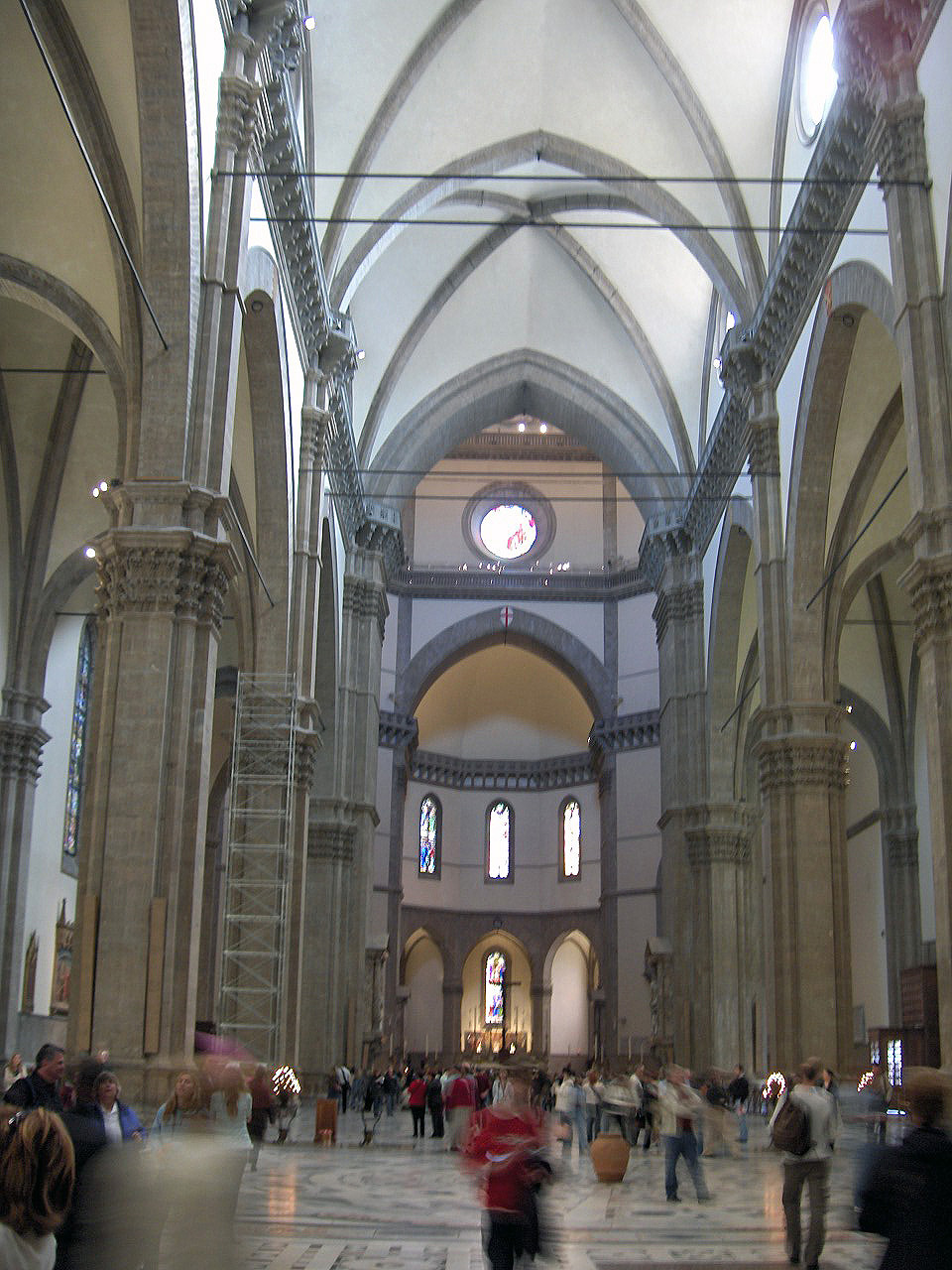 The vast interior nave of Florence Cathedral with Gothic arches and the dome visible at the far end