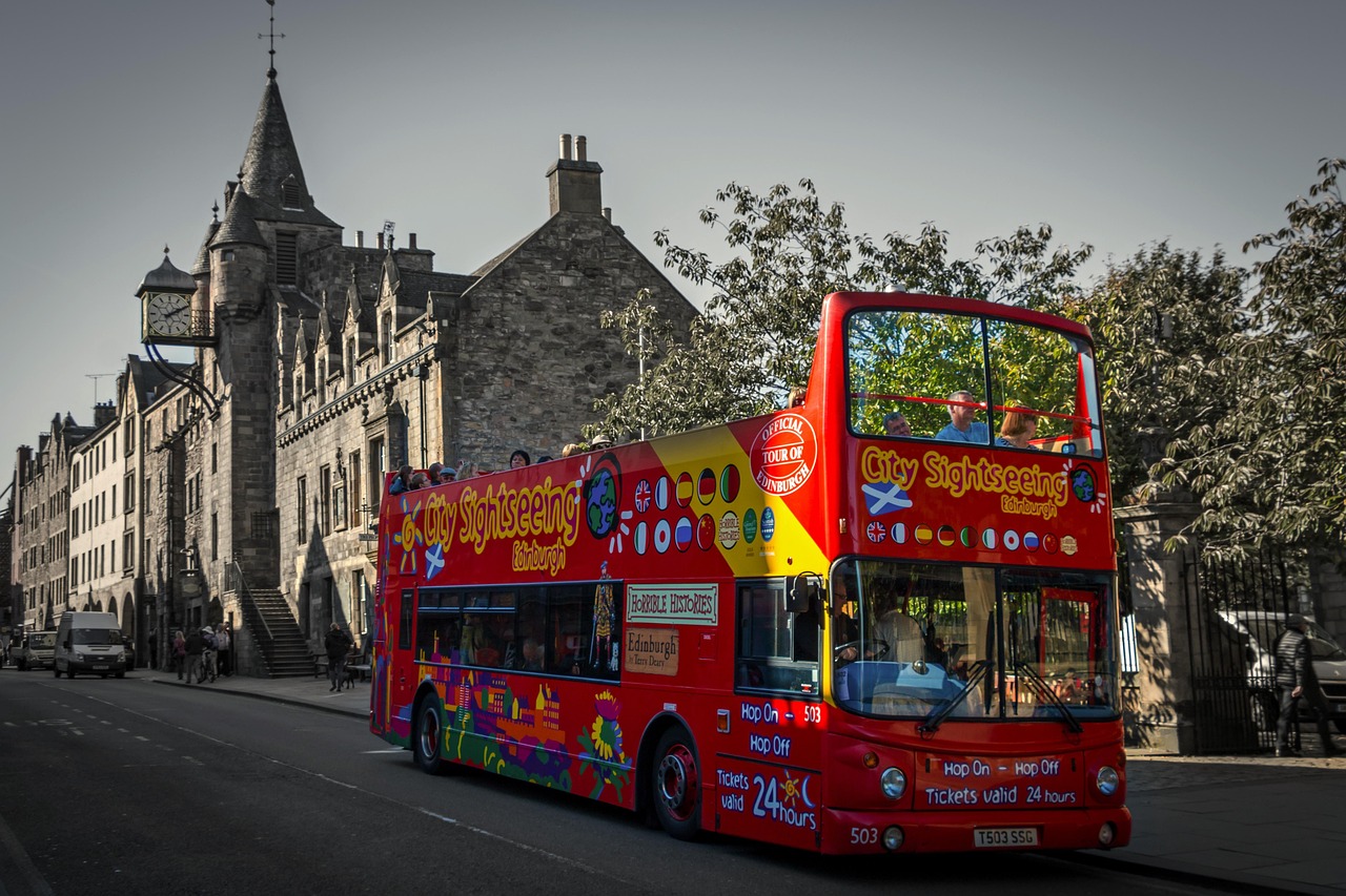 A red sightseeing bus on the Royal Mile in Edinburgh with historic stone buildings