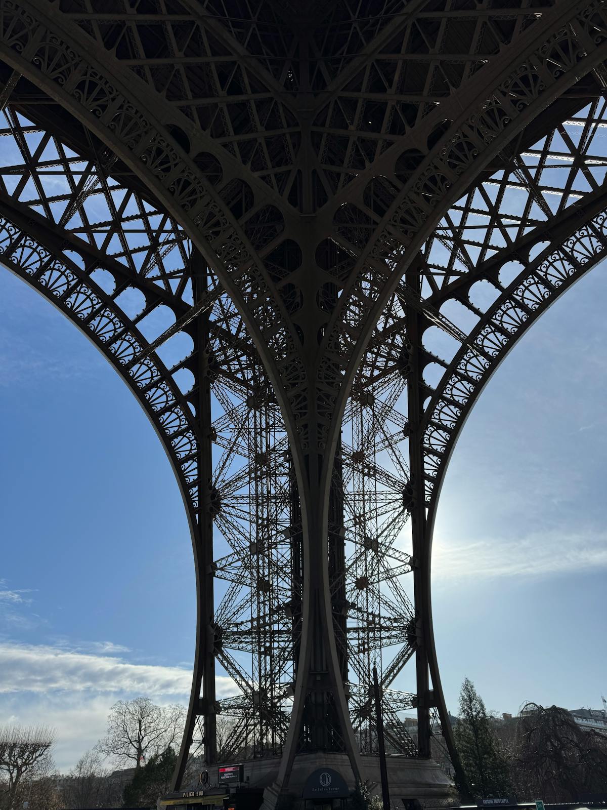 Looking straight up through the intricate iron lattice of the Eiffel Tower