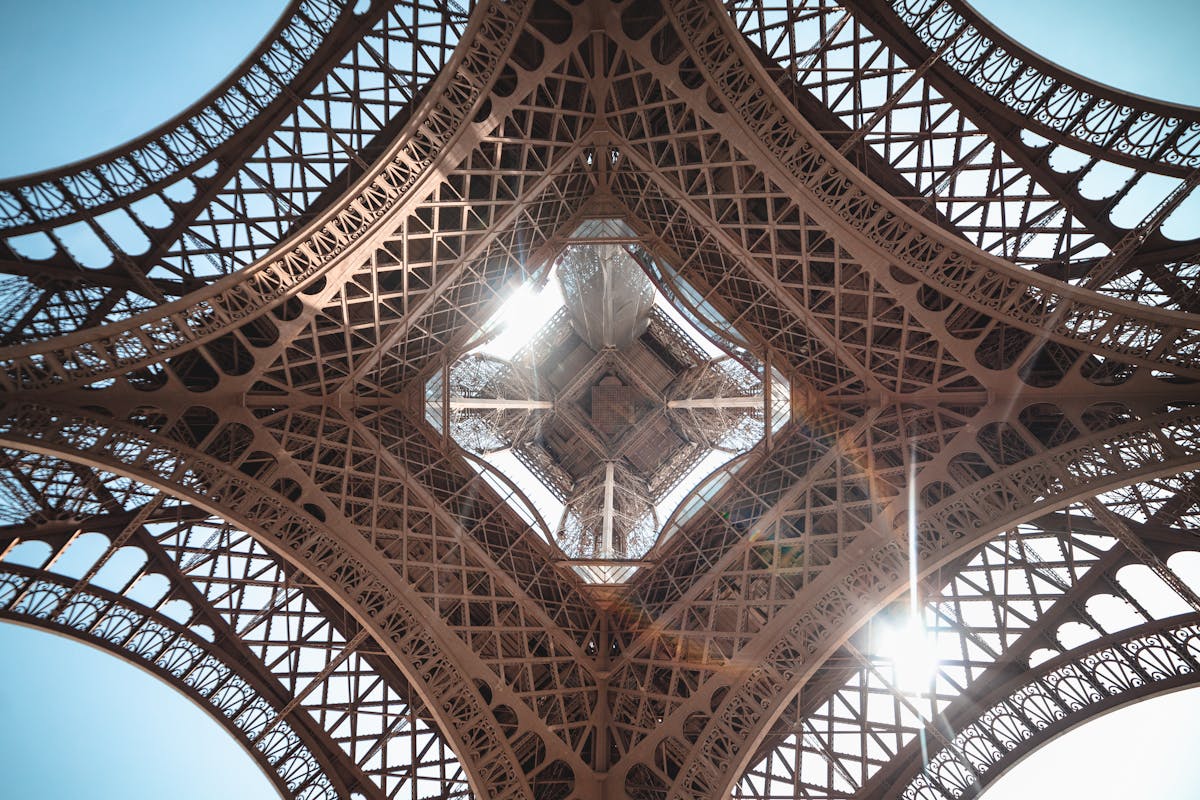 Sunlight streaming through the iron lattice work inside the Eiffel Tower