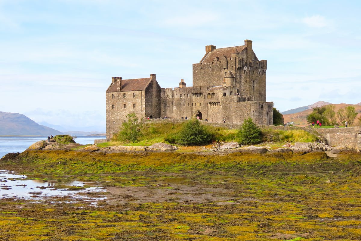 Eilean Donan Castle reflected in still water with mountains behind