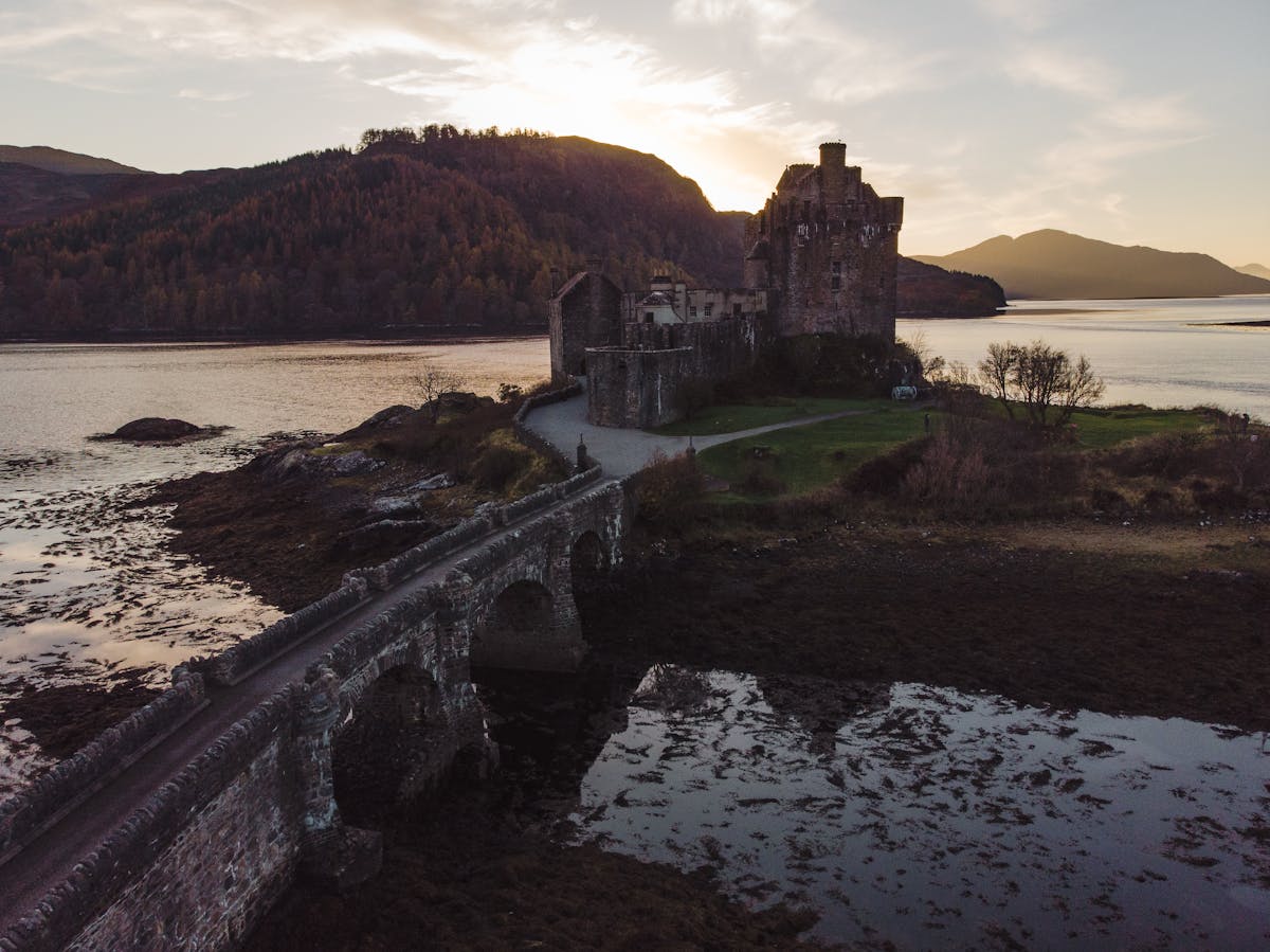 Eilean Donan Castle against Scottish landscape at sunset