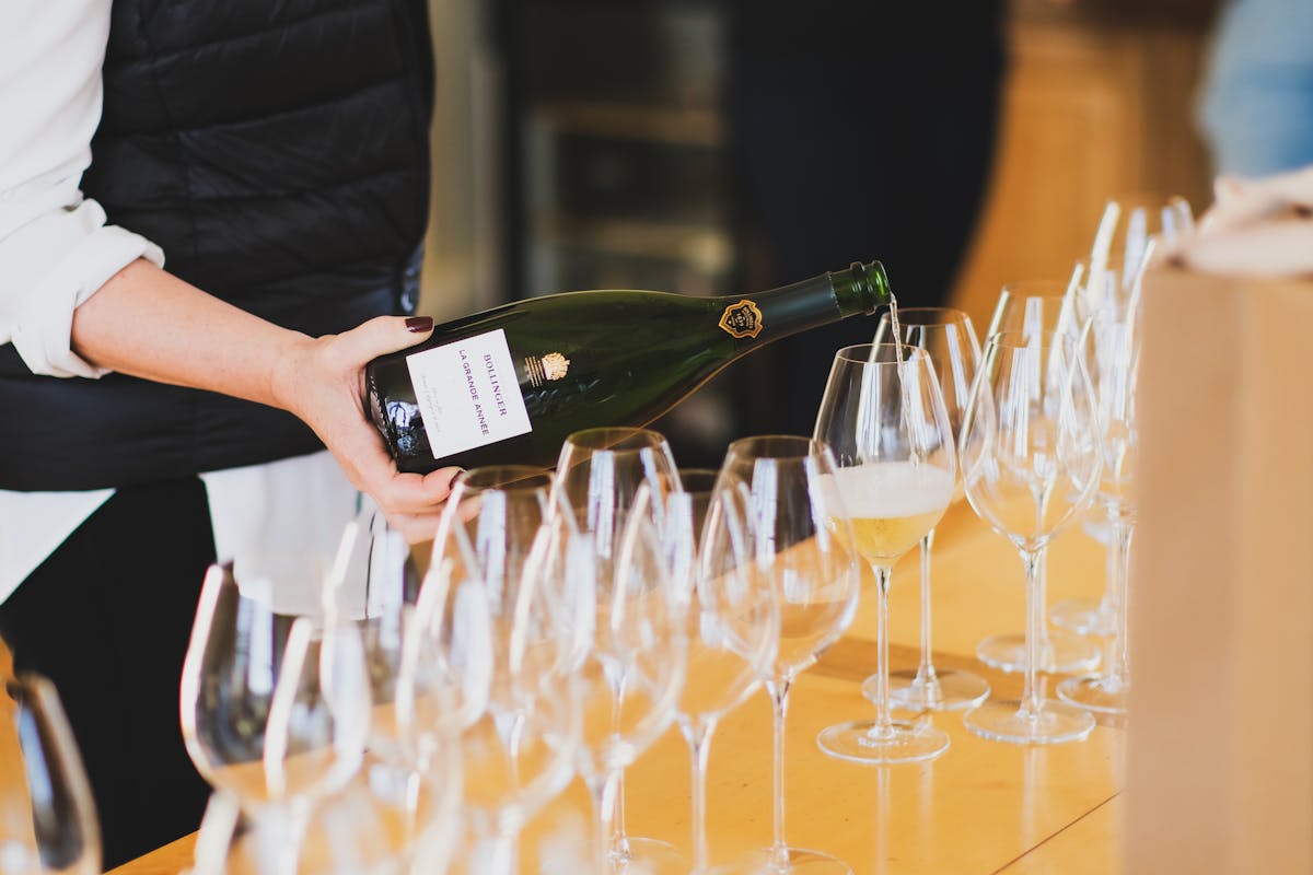 A person pouring champagne into glasses at a tasting in Ay Champagne France