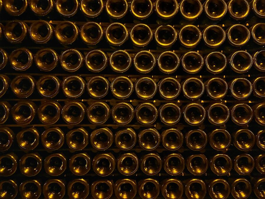 Rows of champagne bottles stacked and aging in a dimly lit underground cellar
