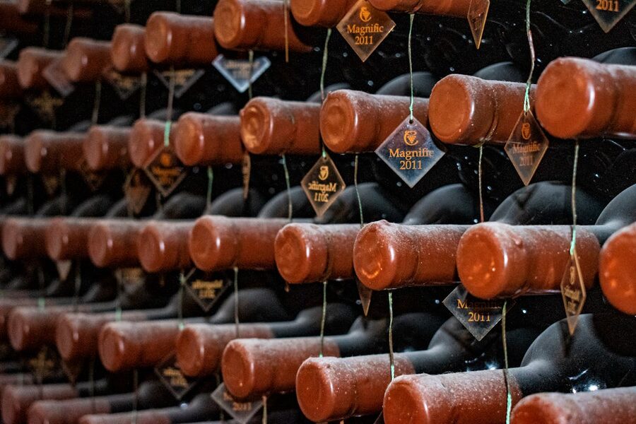 Rows of vintage wine bottles stored horizontally in a dimly lit underground cellar