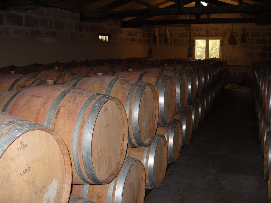 A wine cellar with wooden barrels and wine bottles stored on shelves