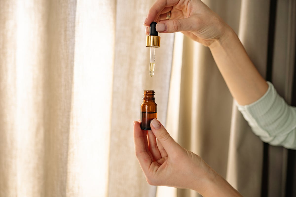 Hands holding a dropper and amber bottle for mixing essential oils