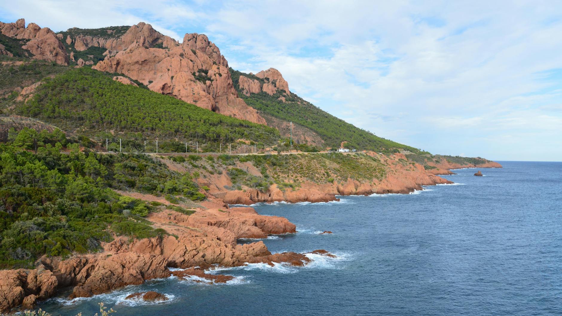 Waves crashing against red Esterel cliffs on the French Riviera coast
