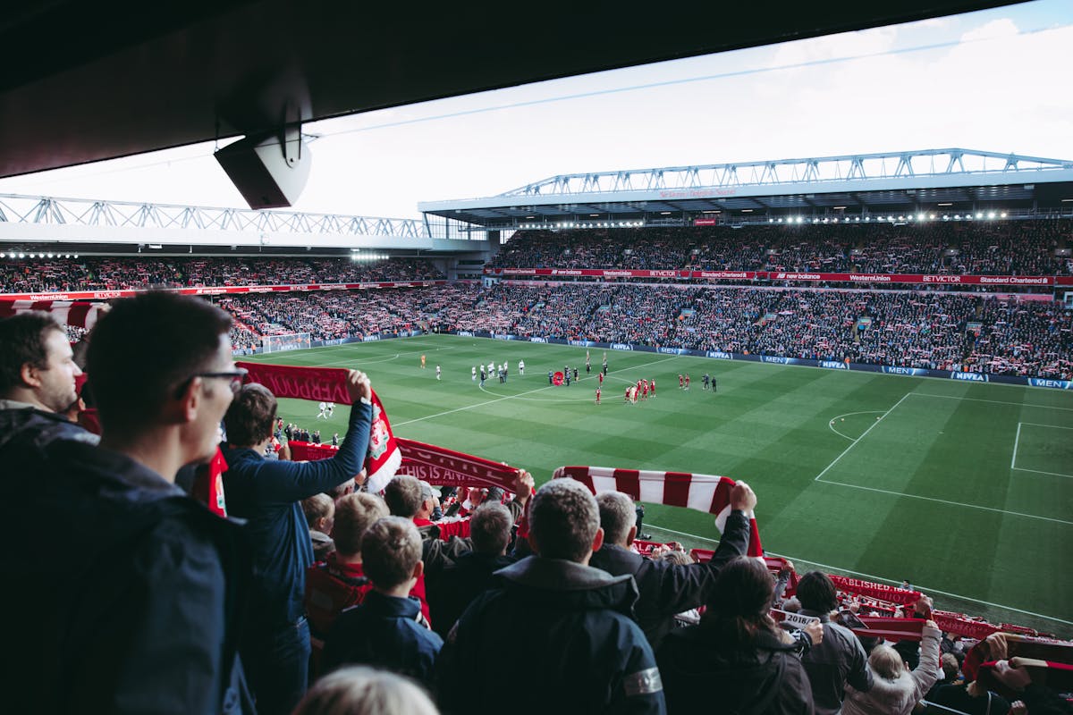 Crowds of excited football fans cheering as players enter the pitch