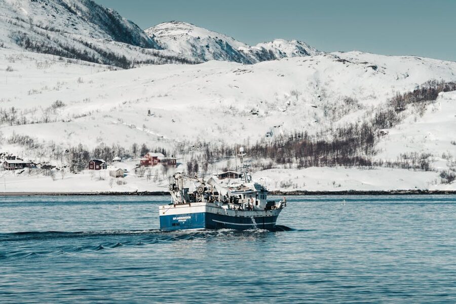Small fishing boat sailing through Norwegian fjord with mountains