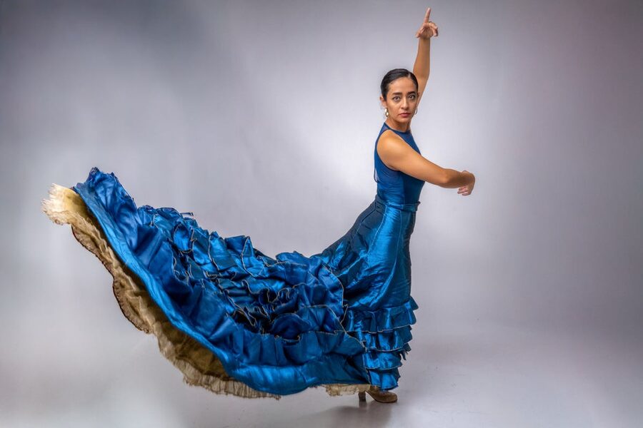 Flamenco dancer performing in a flowing blue dress in a dance studio