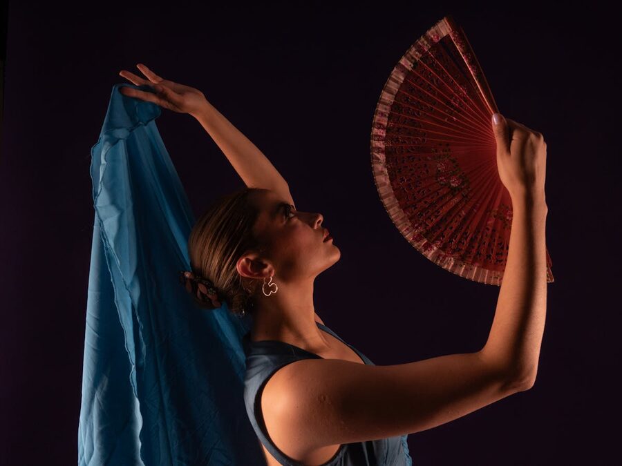 A flamenco dancer posing with a traditional fan and flowing red fabric