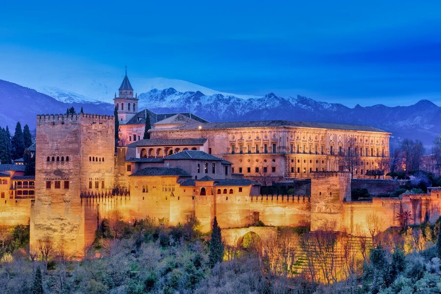 Snow-capped Sierra Nevada mountains behind the illuminated Alhambra palace in Granada