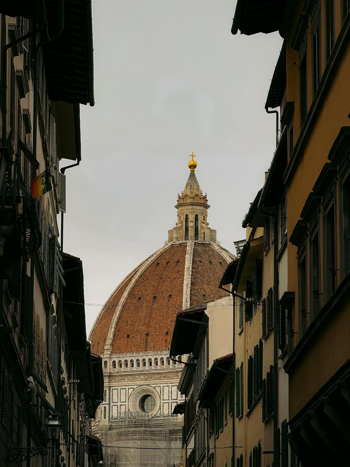View of the Florence Duomo through a narrow street lined with historic Tuscan buildings