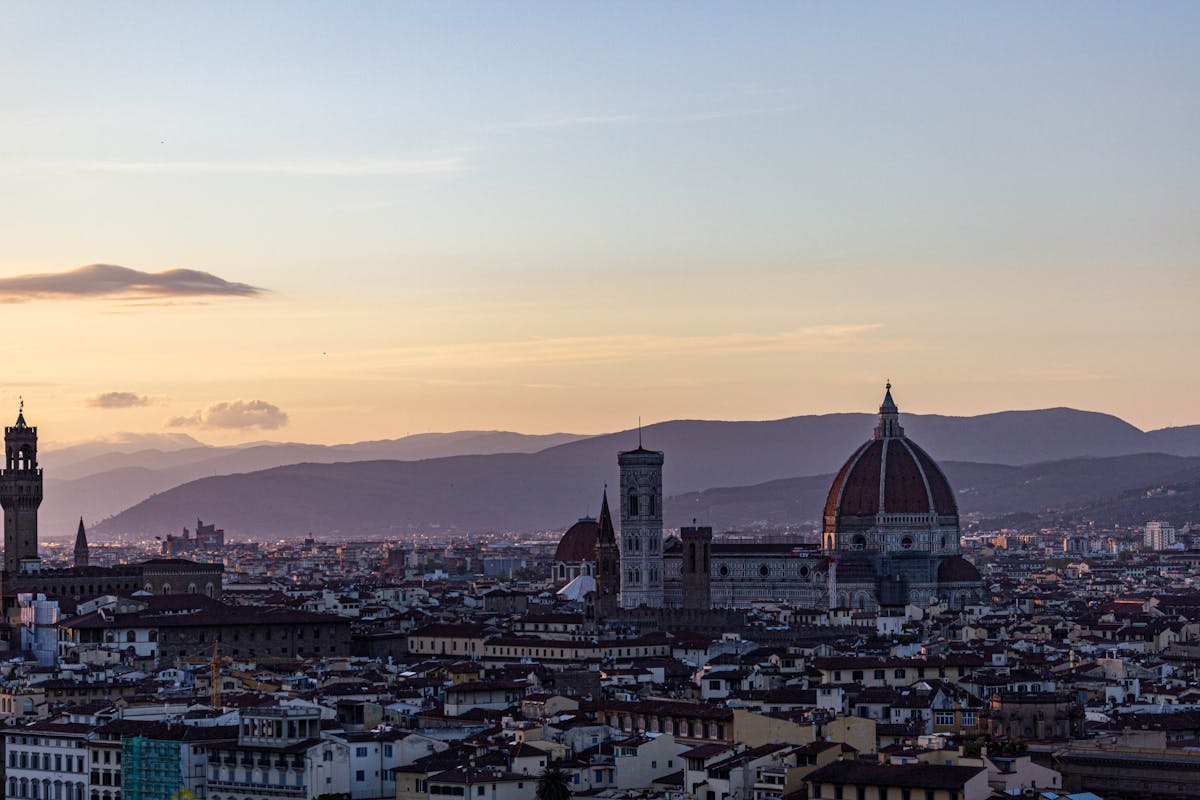 Panoramic view of Florence at sunset showing the Duomo dome rising above the city with mountains in the background