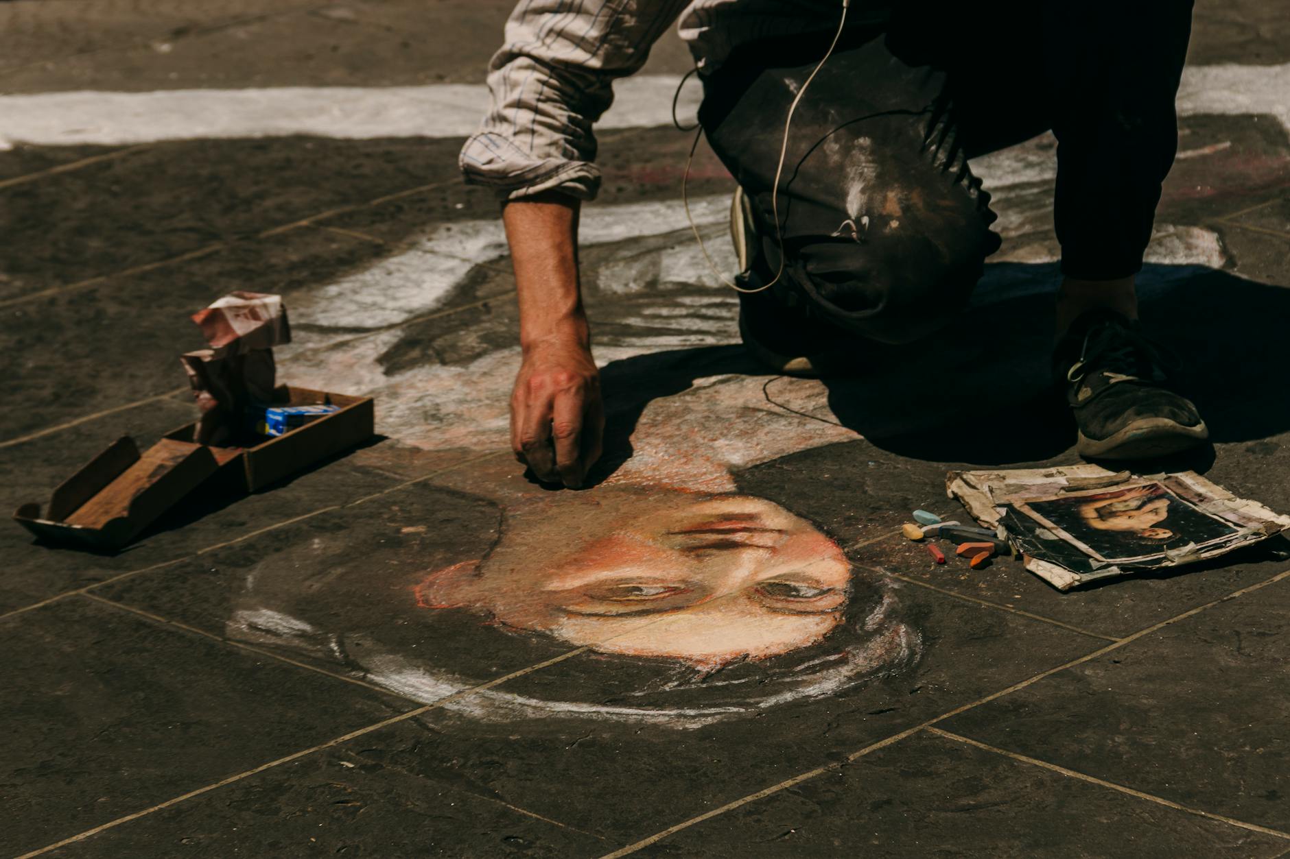 Street artist creating a detailed chalk portrait on pavement in Florence Italy