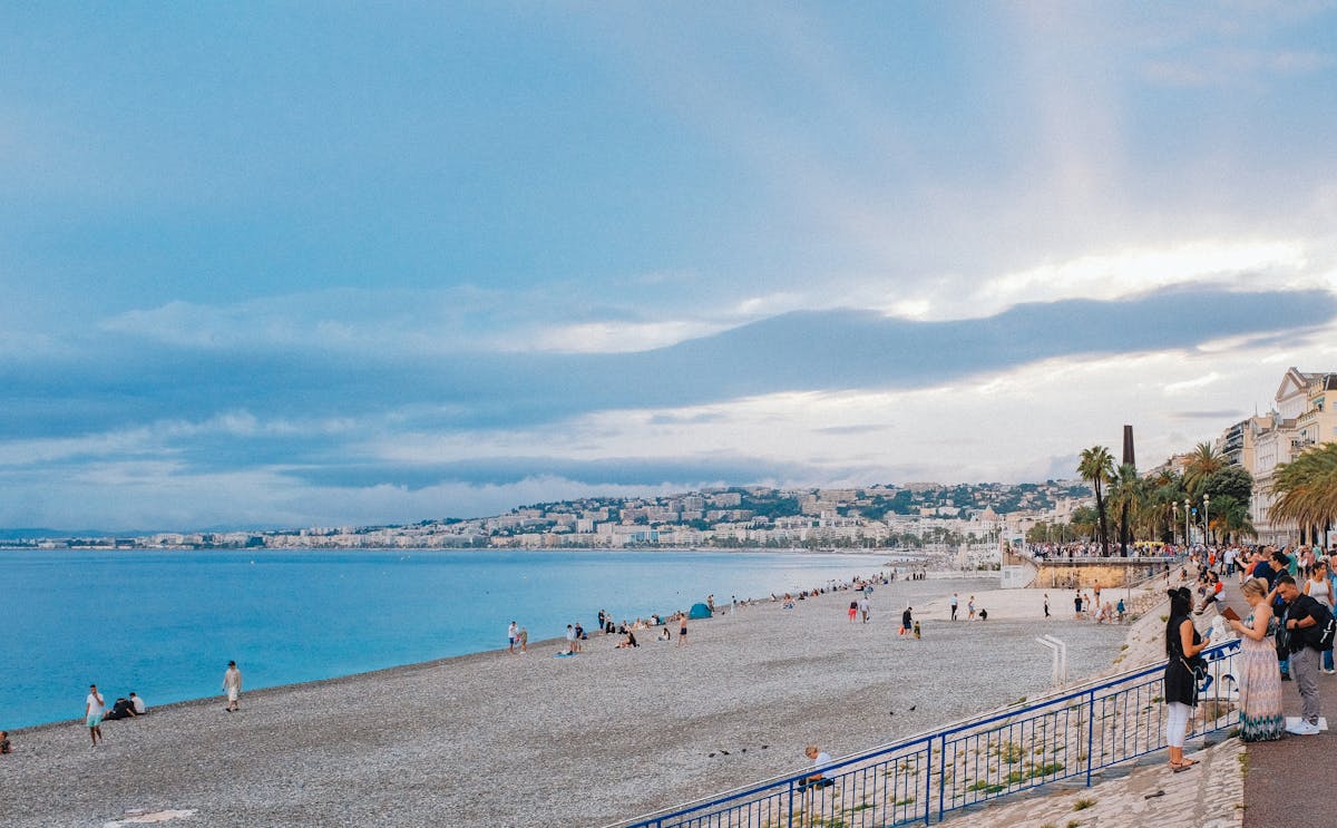 Lively beach scene in Nice France with people enjoying the promenade along the Mediterranean