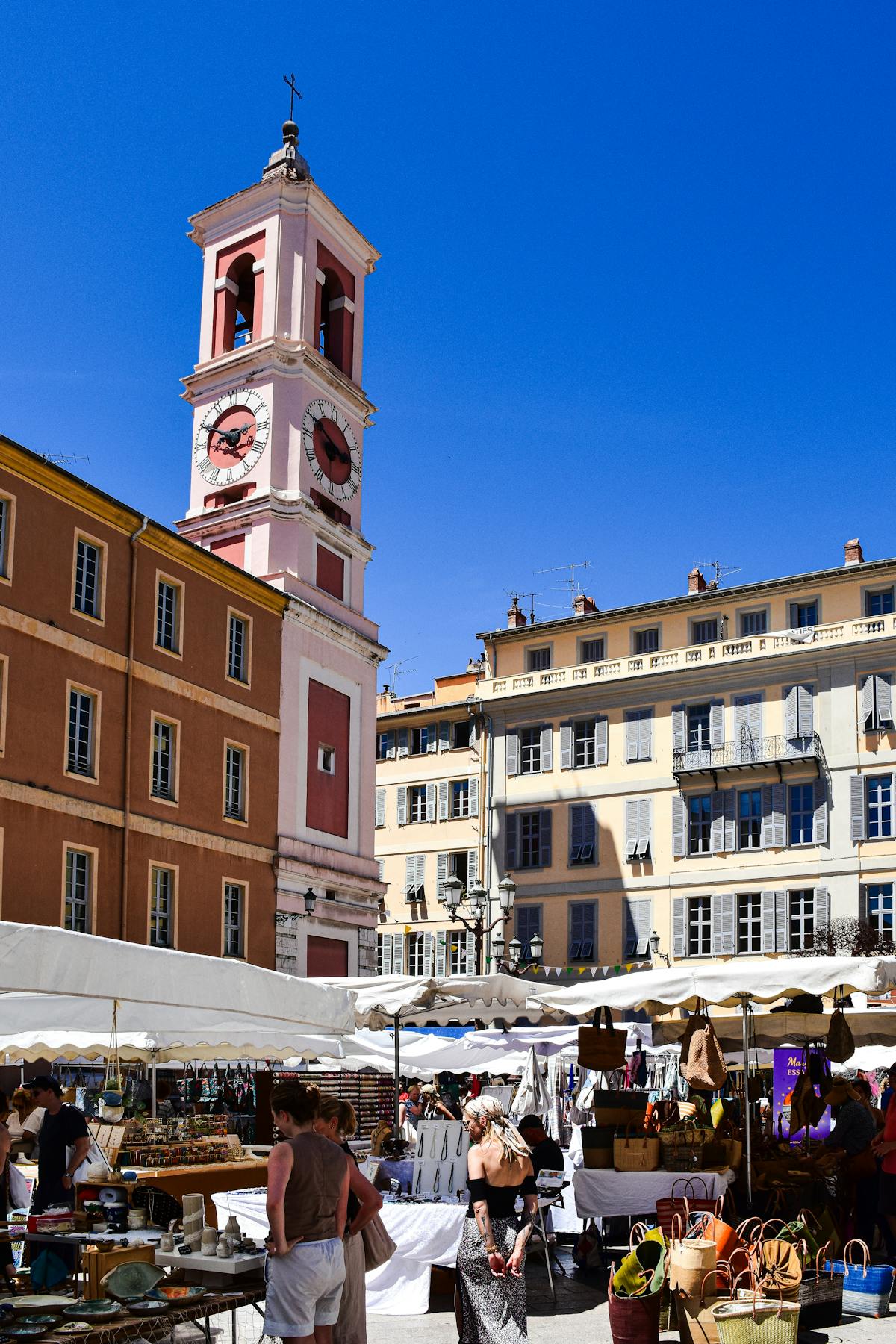 Outdoor market at Cours Saleya in Nice with stalls and palm trees under blue sky