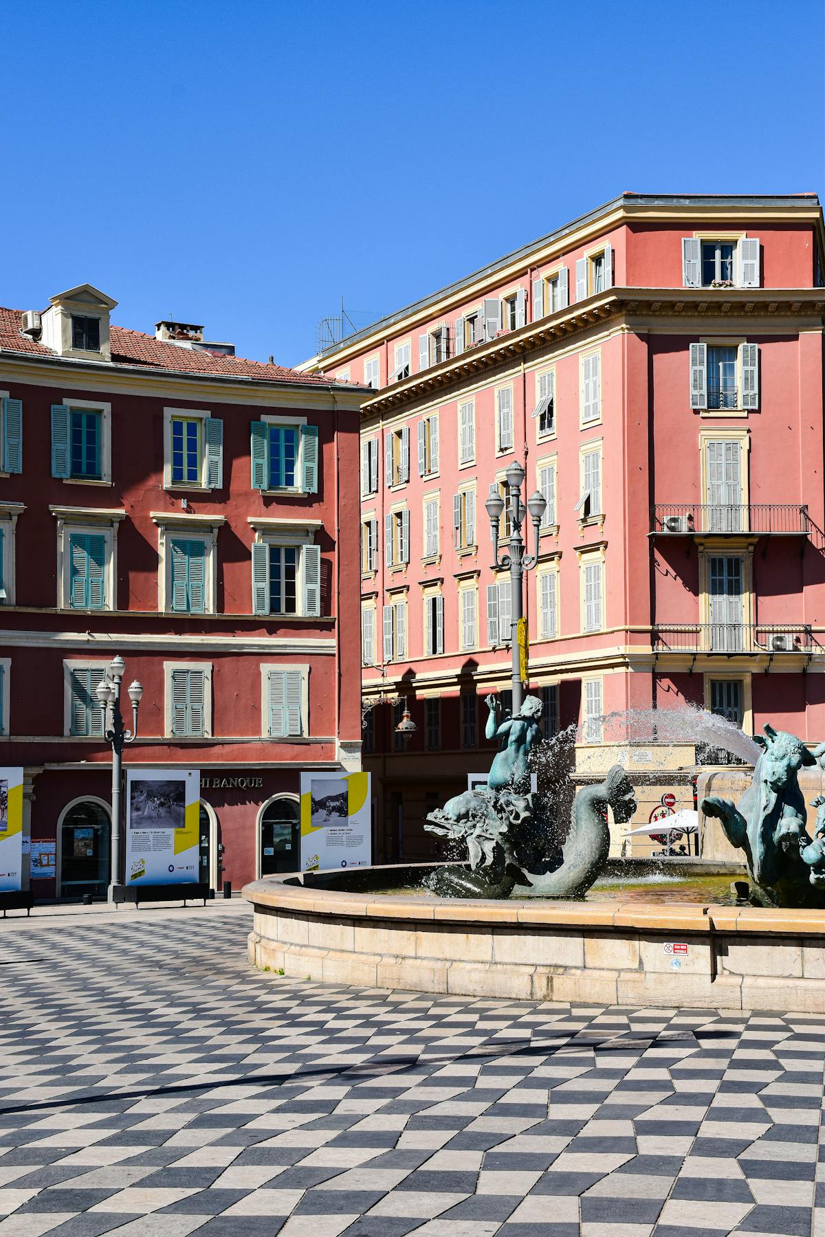 Charming square in Nice old town with historic buildings and fountain under clear blue sky