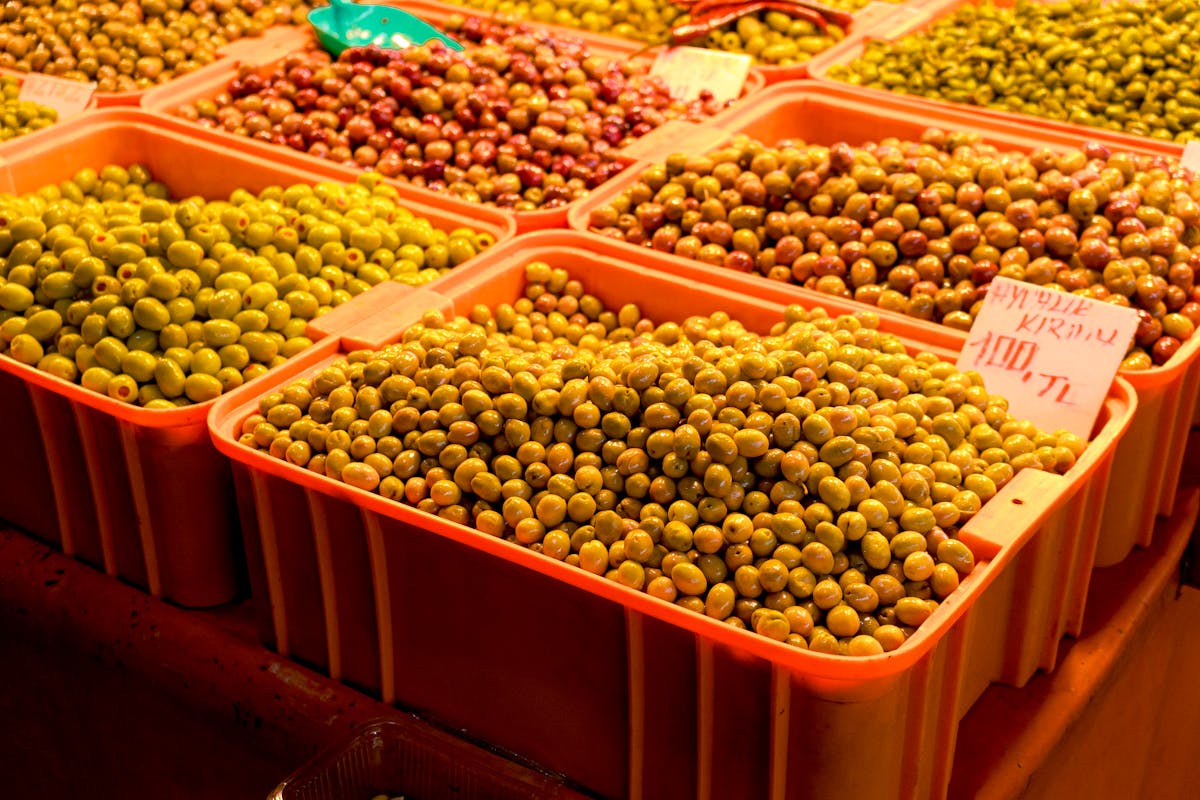 Fresh olives displayed at a street market with various types and preparations