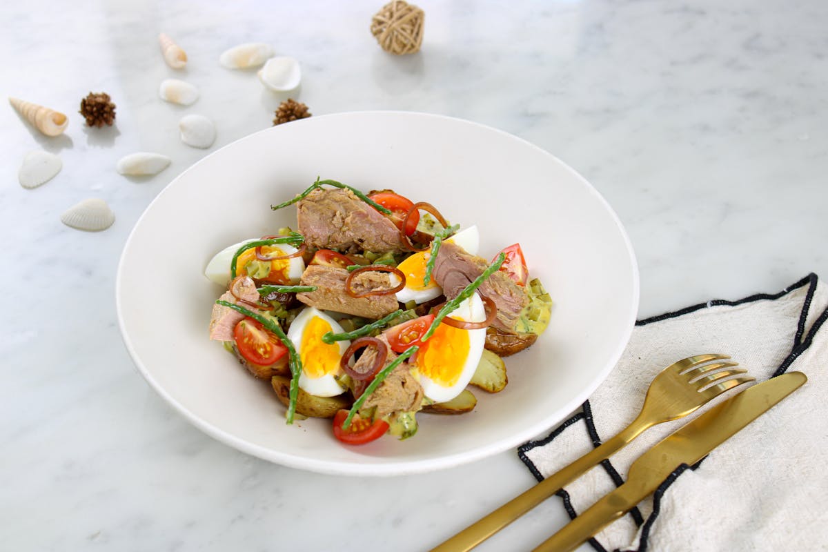 Fresh tuna and egg salad in a white bowl garnished with vegetables