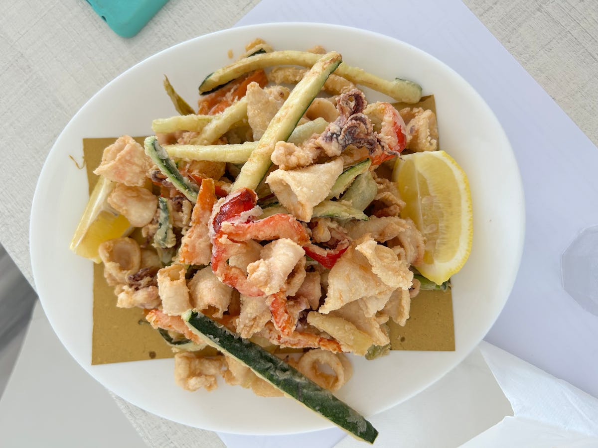 Mixed fried seafood with zucchini and lemon on a white plate