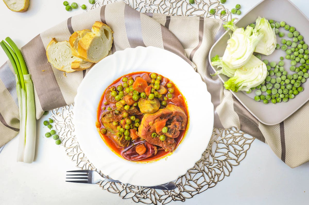 Beef stew with peas carrots and bread on an elegant table setting