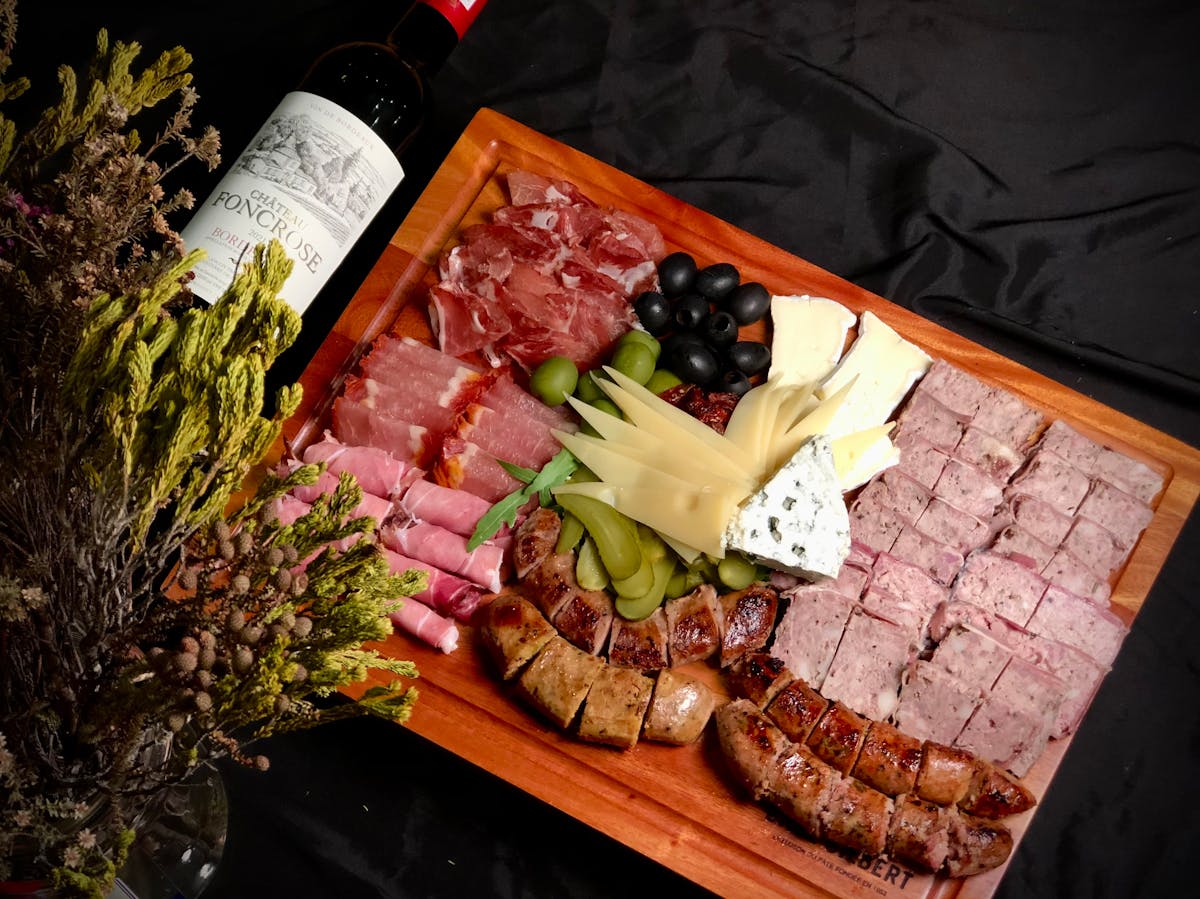 Charcuterie board with assorted meats cheeses and red wine
