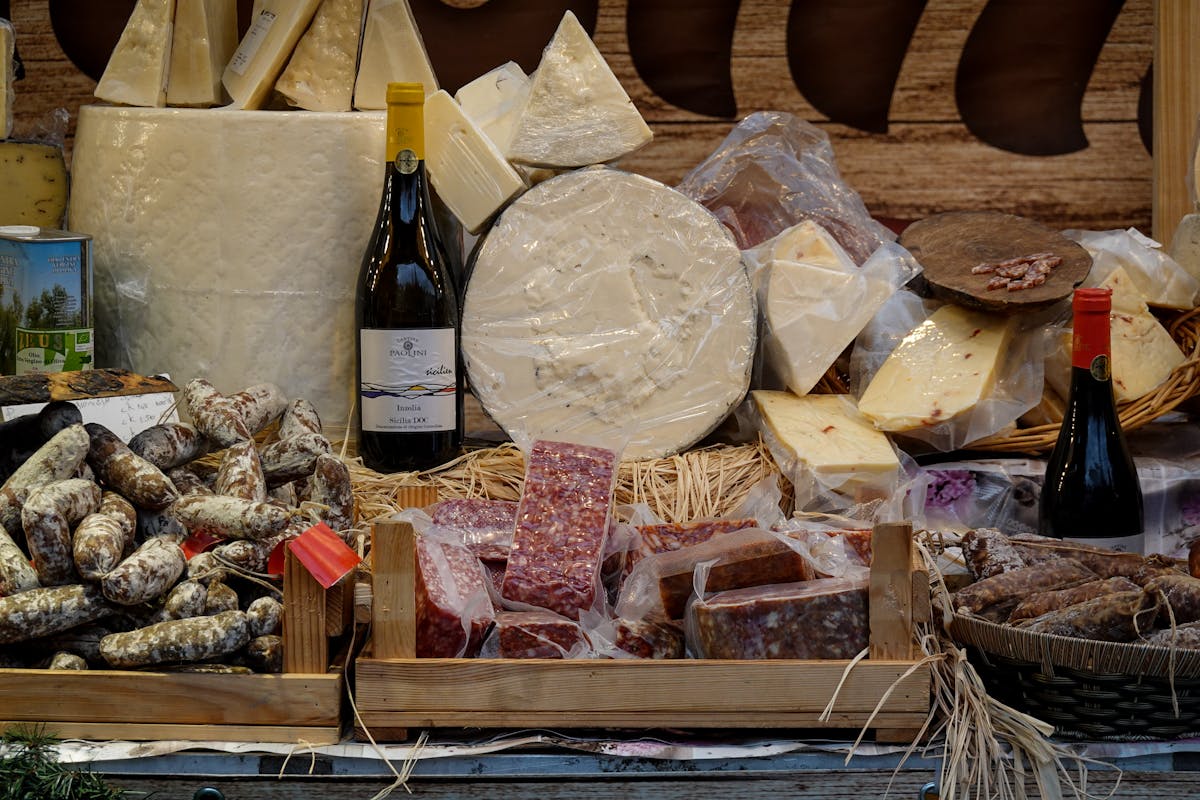 Selection of cheeses sausages and wine bottles at a market