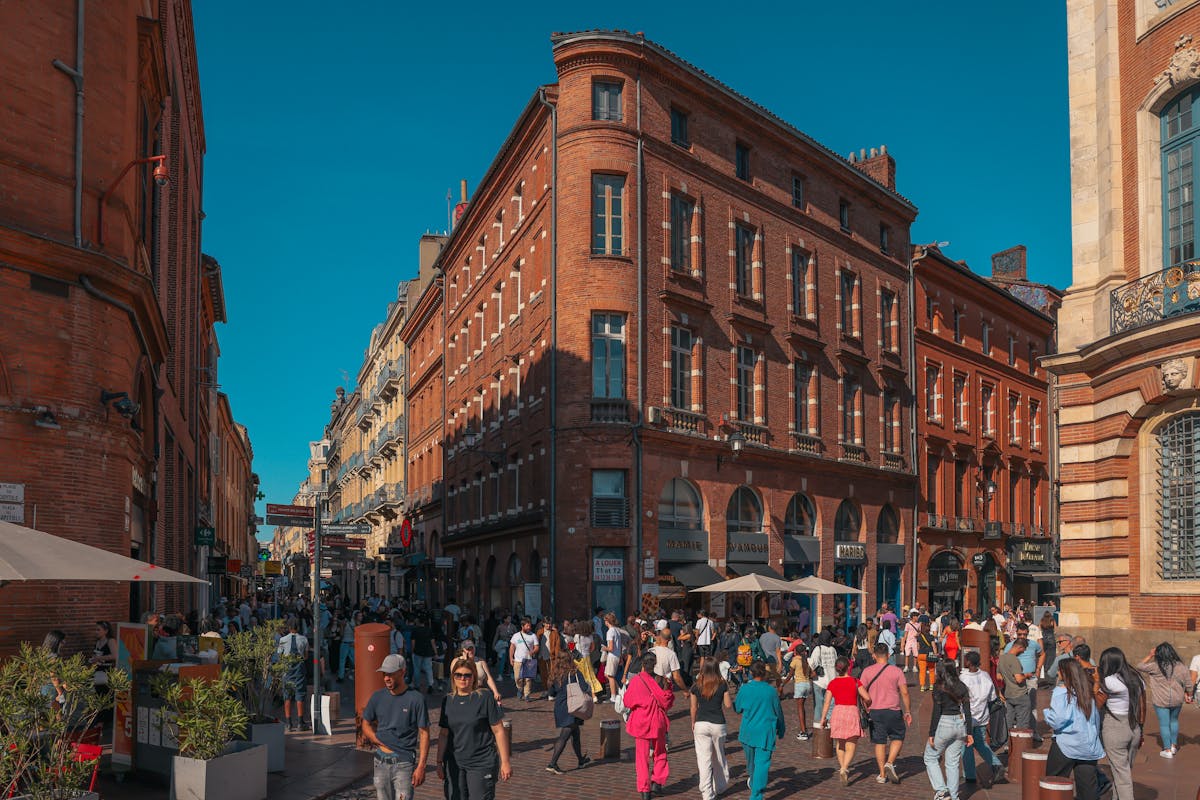 Crowded street in Toulouse historic district with pink brick architecture