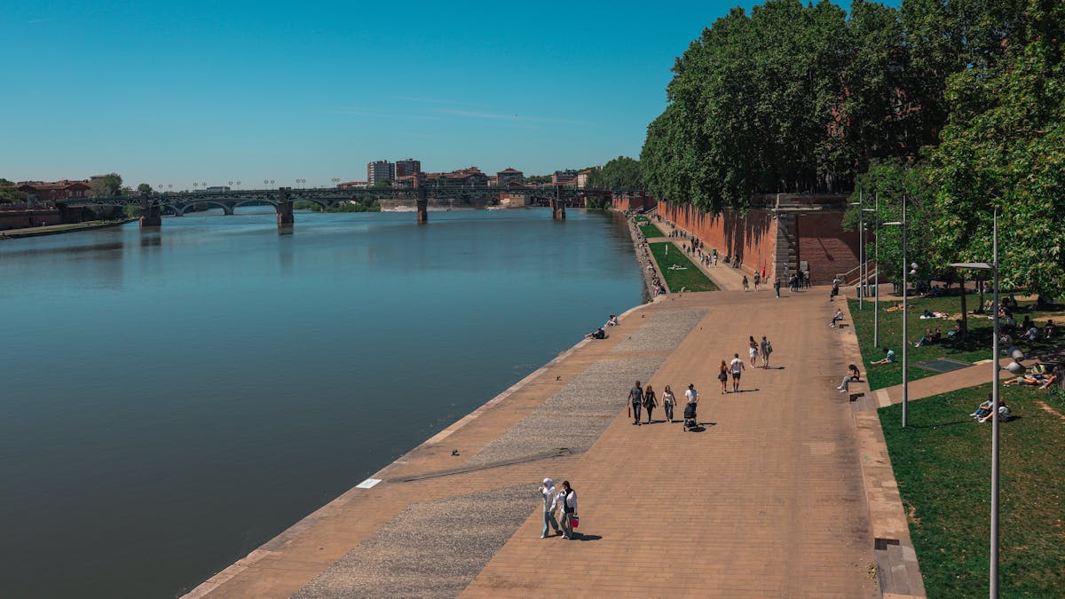 People strolling along the Garonne River walkway in Toulouse on a sunny day