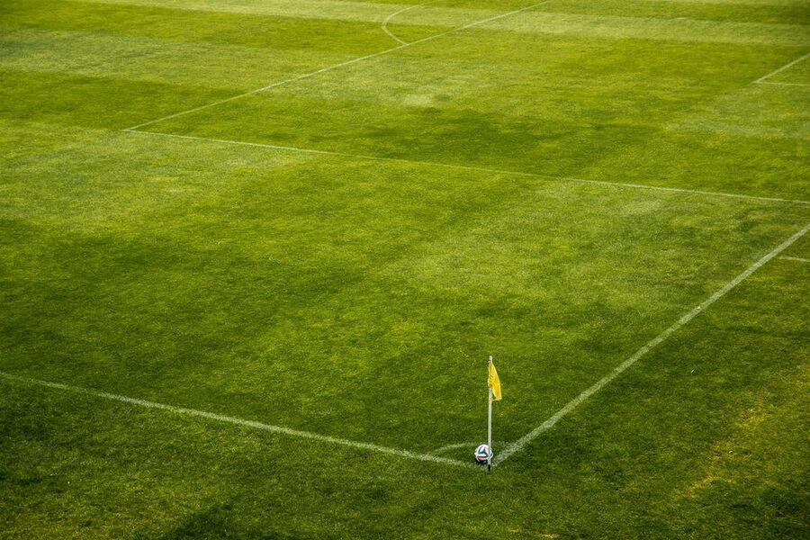 Corner flag and ball on a green football pitch