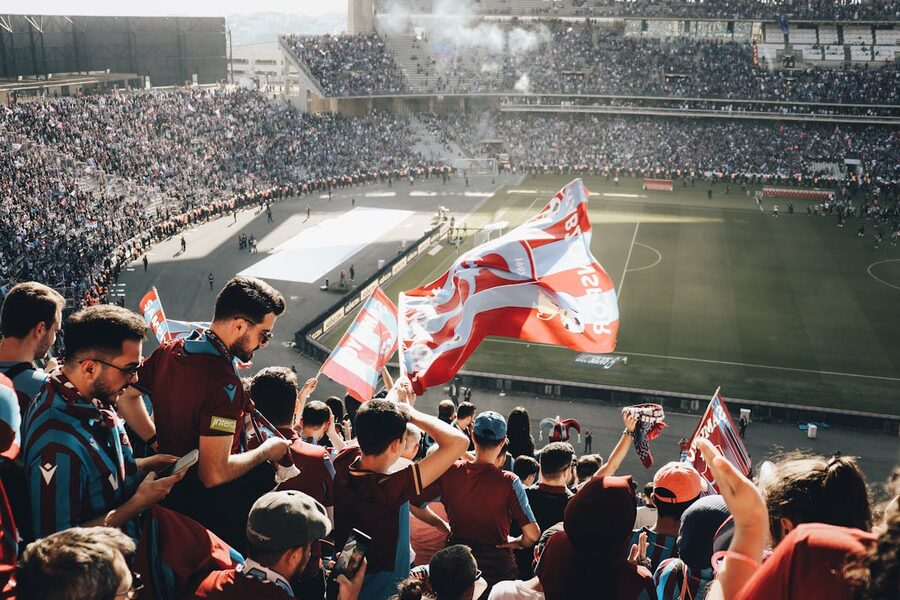 Football fans with flags cheering in a stadium during daytime