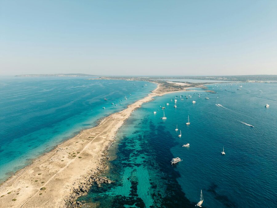 Aerial view of Formentera island coastline with turquoise Mediterranean waters and sailing boats