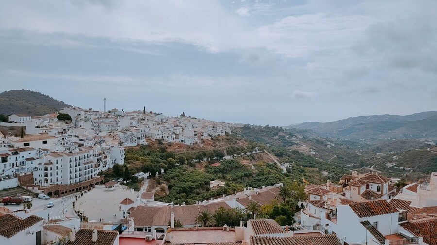 Aerial photograph of Frigiliana showing white buildings scattered across a green hillside in Andalusia