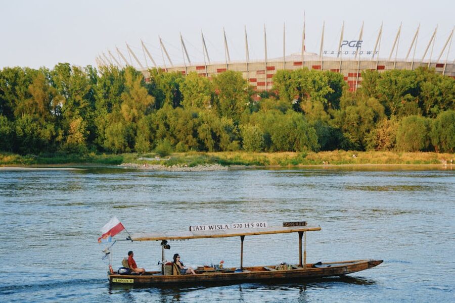 Wooden boat on the Vistula in Warsaw with the National Stadium in the background
